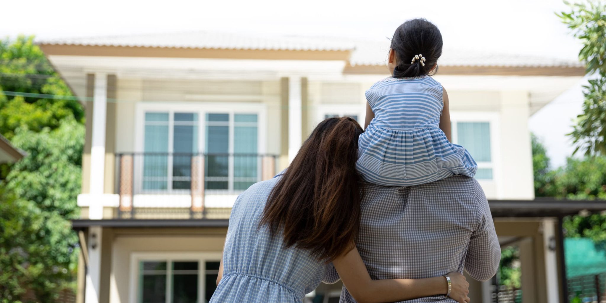 Happy Asian family. Father, mother and daughter near new home. Real estate background with copy space